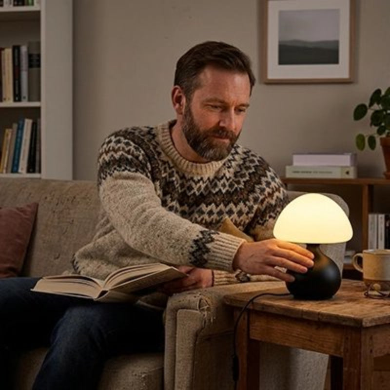 Lampe champignon noir avec homme qui lit un livre